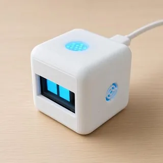 White cube-shaped desk robot with glowing blue eyes on a wooden desk